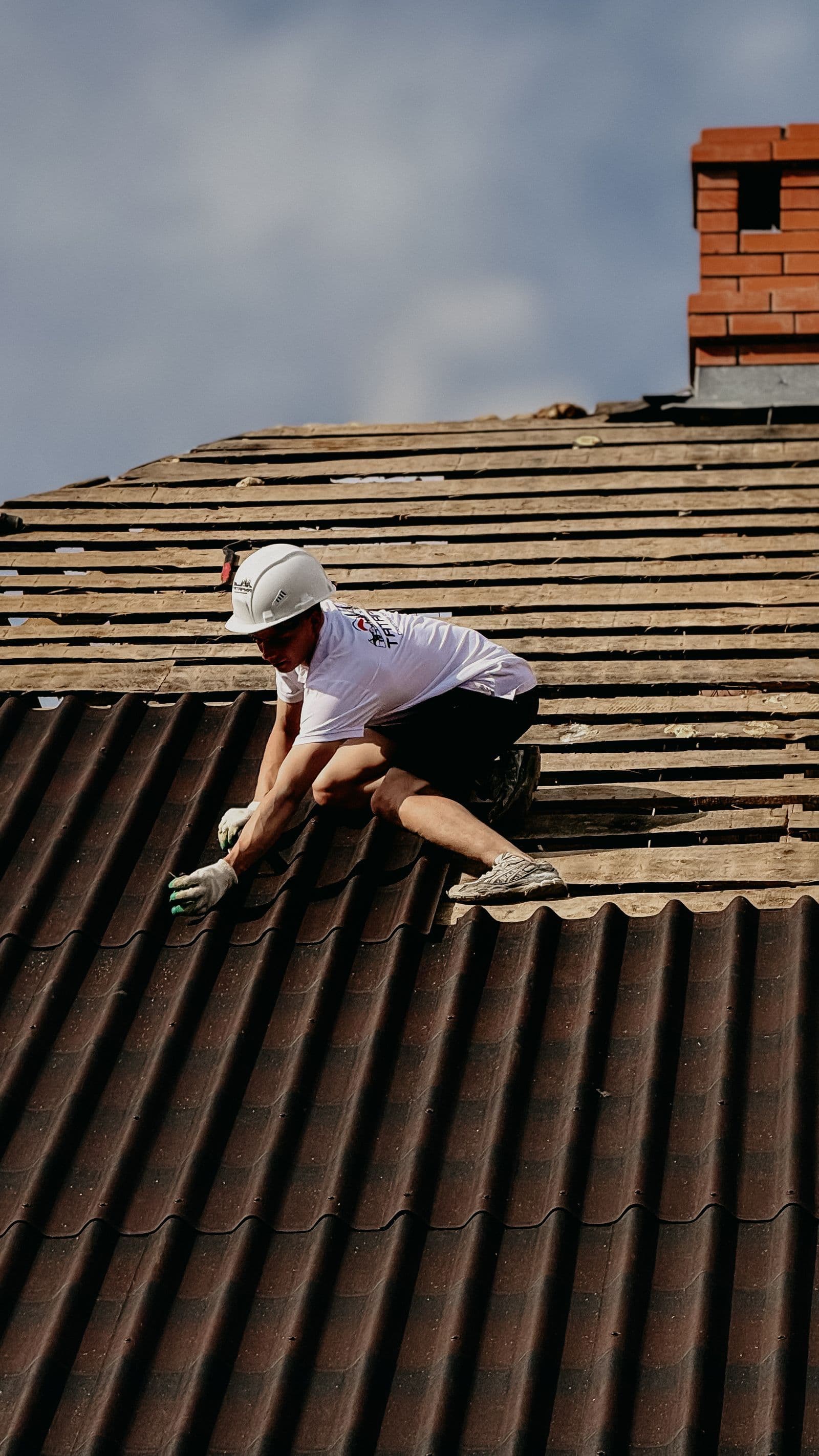 Roofer installing tiles on a pitched roof wearing safety gear